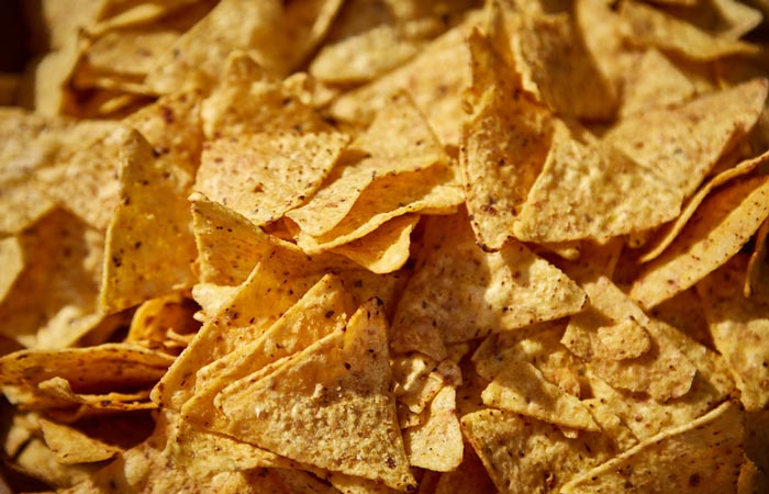 Totopos caseros dorados y crujientes sobre papel absorbente, el primer paso para saber cómo hacer chilaquiles.